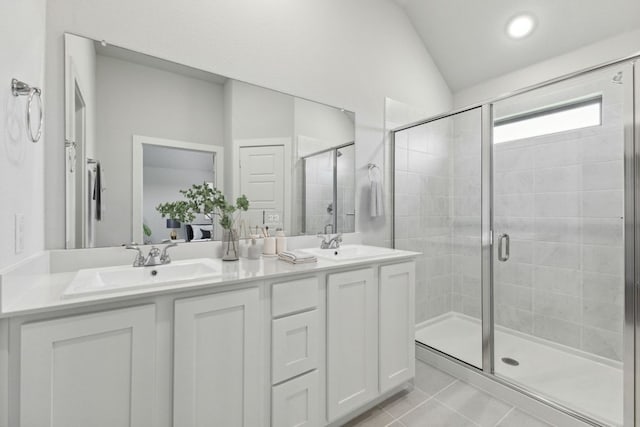212 Hidalgo Ln, Elgin, TX 78621 - bathroom featuring a shower stall, double vanity, tile patterned flooring, and vaulted ceiling