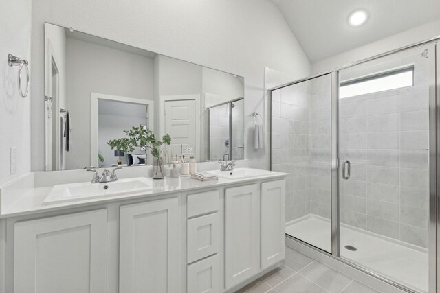 212 Hidalgo Ln, Elgin, TX 78621 - full bathroom featuring double vanity, a shower stall, tile patterned flooring, and vaulted ceiling