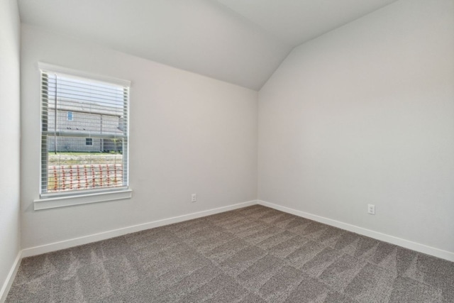 212 Hidalgo Ln, Elgin, TX 78621 - empty room with dark carpet, vaulted ceiling, and baseboards