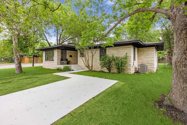 view of front of house featuring central air condition unit, a front yard, and stone siding