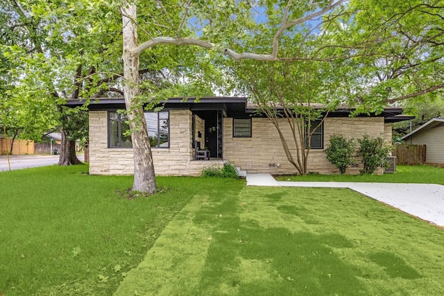 ranch-style house featuring fence, stone siding, and a front lawn