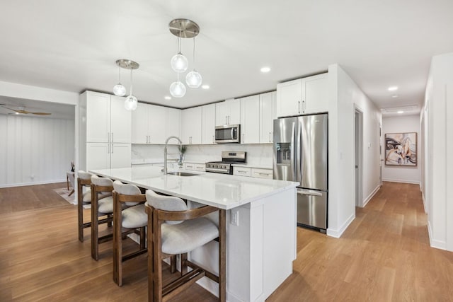 kitchen featuring a sink, appliances with stainless steel finishes, light wood finished floors, and white cabinetry