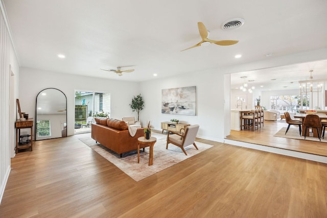 living area with ceiling fan with notable chandelier, recessed lighting, and light wood-style flooring
