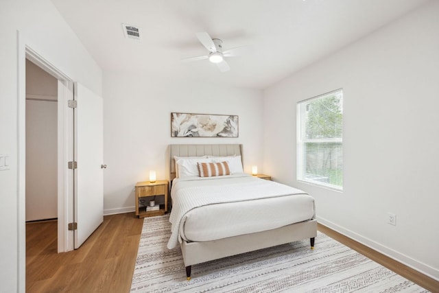 bedroom featuring ceiling fan, baseboards, visible vents, and wood finished floors