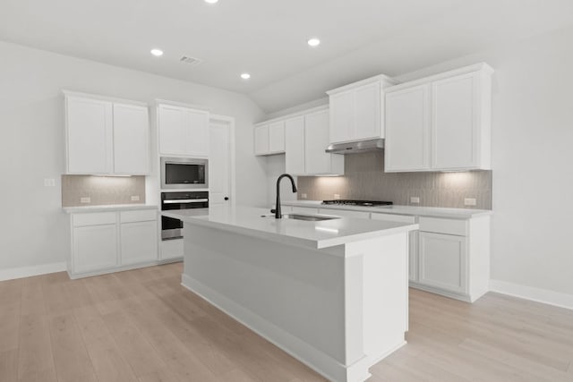 314 Five Mile Creek Way, Kyle, TX 78640 - kitchen featuring stainless steel appliances, a sink, under cabinet range hood, a center island with sink, and backsplash