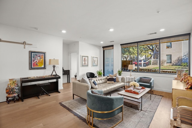 living room with a barn door and light wood-type flooring