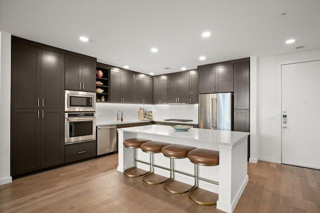 kitchen with light hardwood / wood-style floors, a center island, a kitchen bar, sink, and stainless steel appliances