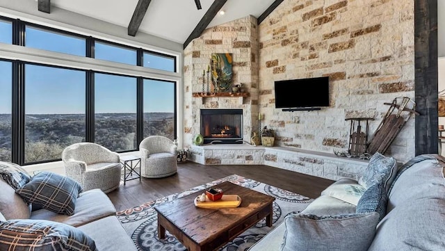 living room with high vaulted ceiling, hardwood / wood-style flooring, beam ceiling, and a stone fireplace