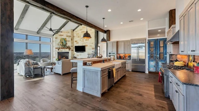 kitchen featuring a spacious island, decorative light fixtures, high vaulted ceiling, high end appliances, and beam ceiling