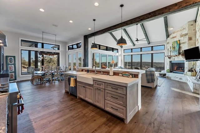 kitchen featuring decorative light fixtures, beamed ceiling, an island with sink, sink, and high vaulted ceiling