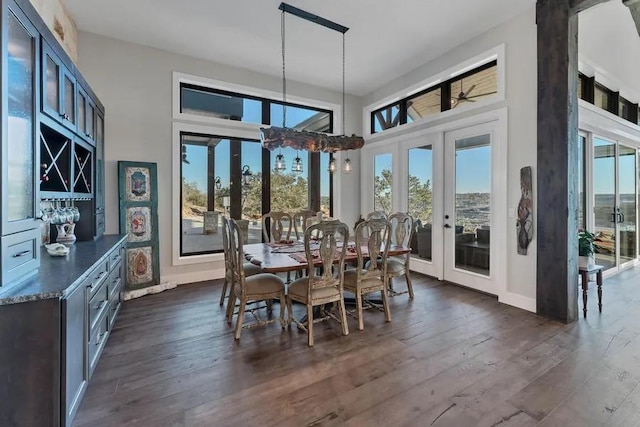 dining space with dark hardwood / wood-style flooring, a towering ceiling, and french doors