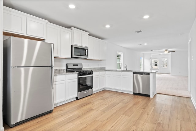 kitchen featuring sink, light hardwood / wood-style flooring, appliances with stainless steel finishes, white cabinets, and light stone counters