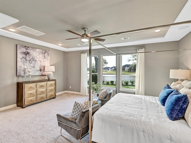 carpeted bedroom with ceiling fan, a water view, and a raised ceiling