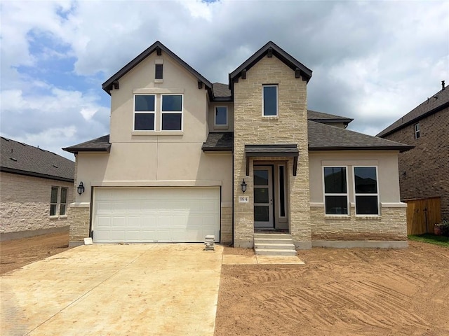 traditional-style house featuring an attached garage, driveway, stucco siding, and stone siding
