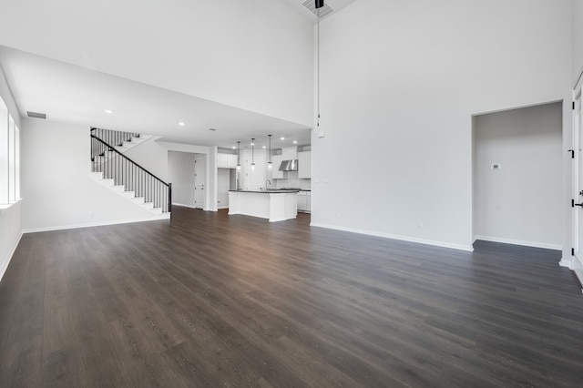 184 Milam Creek Dr, Kyle, TX 78640 - unfurnished living room with dark wood-type flooring, baseboards, stairs, a high ceiling, and recessed lighting
