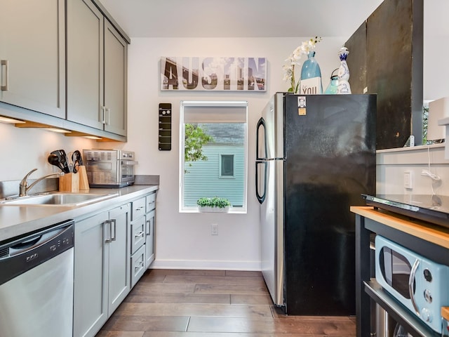 kitchen featuring appliances with stainless steel finishes, gray cabinetry, dark hardwood / wood-style floors, and sink