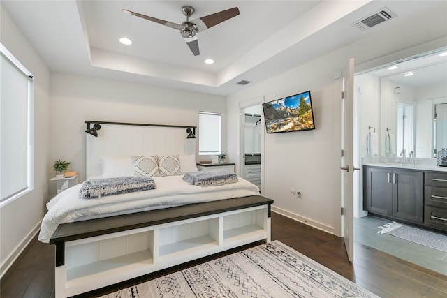 bedroom with ceiling fan, dark hardwood / wood-style floors, multiple windows, and a raised ceiling