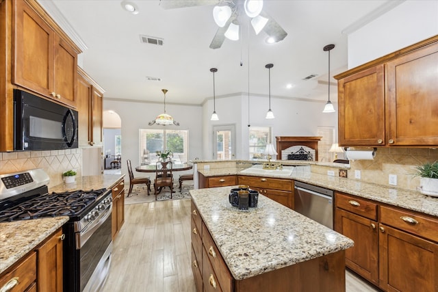 kitchen with stainless steel appliances, tasteful backsplash, a center island, and decorative light fixtures