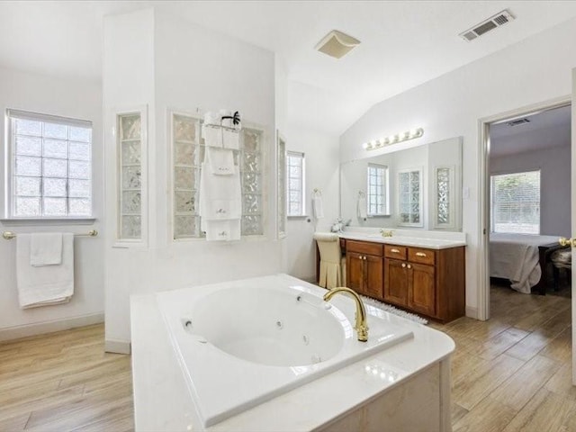 bathroom featuring vaulted ceiling, wood-type flooring, plenty of natural light, and vanity