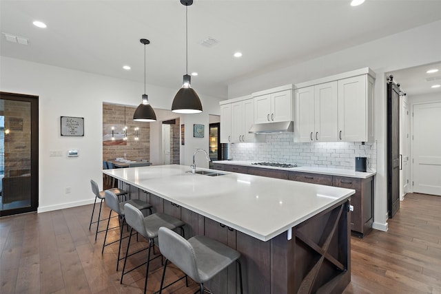 kitchen with white cabinetry, sink, backsplash, hanging light fixtures, and a large island