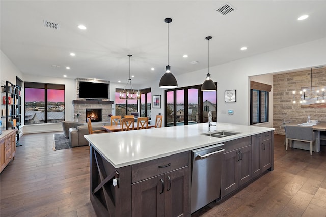 kitchen featuring a center island with sink, decorative light fixtures, a chandelier, stainless steel dishwasher, and sink