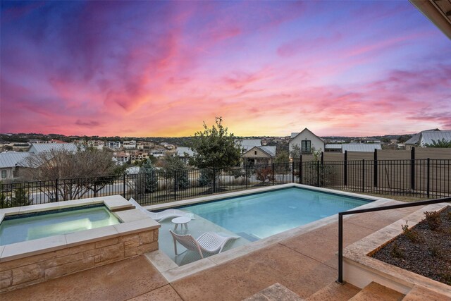 pool at dusk with an in ground hot tub and a patio