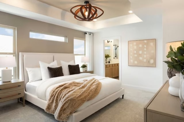 carpeted bedroom with ensuite bathroom and a raised ceiling