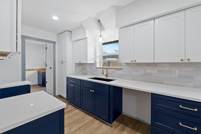 kitchen featuring sink, white cabinetry, blue cabinetry, and light hardwood / wood-style floors