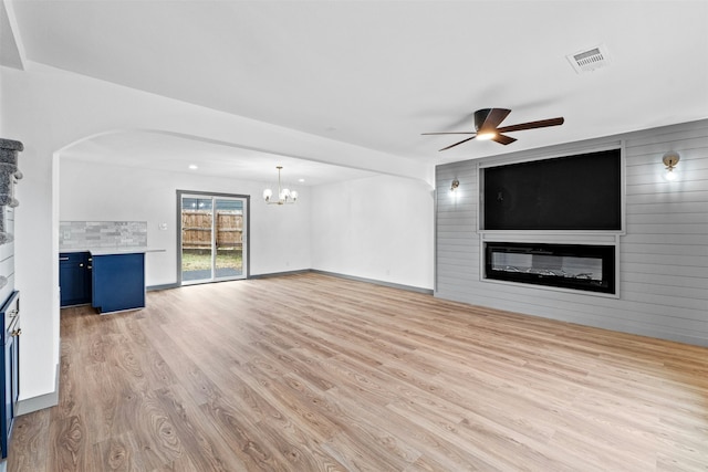 unfurnished living room featuring a fireplace, light hardwood / wood-style floors, and ceiling fan with notable chandelier