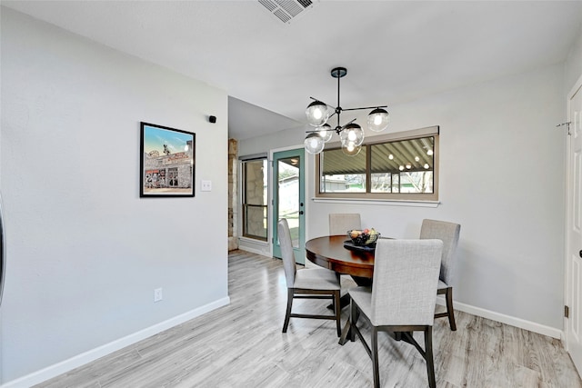 dining space with light hardwood / wood-style floors and a notable chandelier