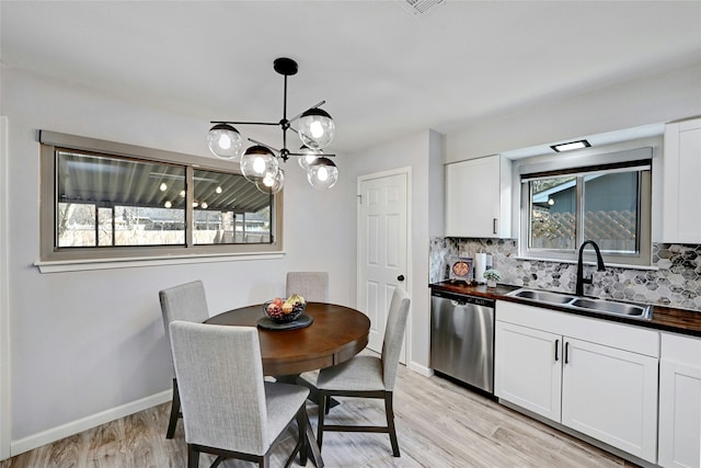 dining area featuring light wood-type flooring, a chandelier, and sink