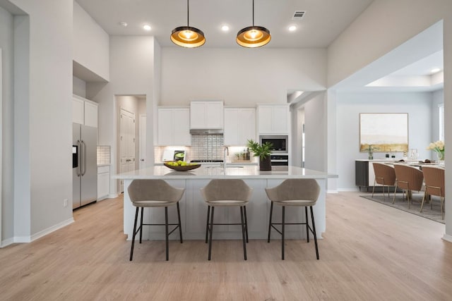 305 Five Mile Creek Way, Kyle, TX 78640 - kitchen featuring appliances with stainless steel finishes, decorative backsplash, a high ceiling, white cabinetry, and light countertops