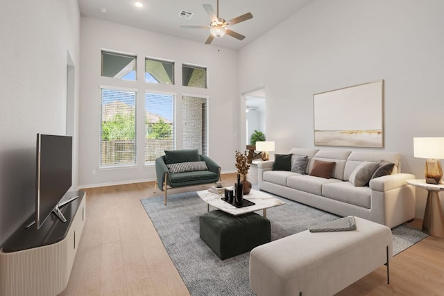 305 Five Mile Creek Way, Kyle, TX 78640 - living area with a ceiling fan, light wood-style floors, a high ceiling, and baseboards