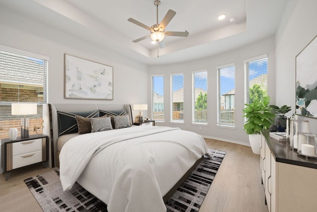 305 Five Mile Creek Way, Kyle, TX 78640 - bedroom featuring a raised ceiling, multiple windows, light wood-type flooring, and recessed lighting