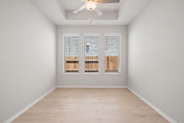 305 Five Mile Creek Way, Kyle, TX 78640 - empty room with light wood-style flooring, ceiling fan, a tray ceiling, and baseboards