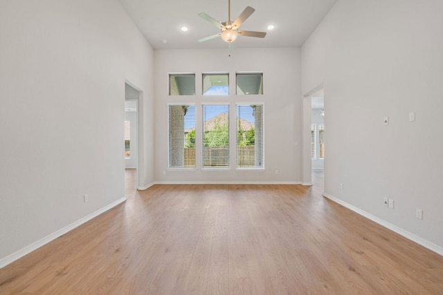305 Five Mile Creek Way, Kyle, TX 78640 - unfurnished living room with ceiling fan, light wood-type flooring, a high ceiling, baseboards, and recessed lighting