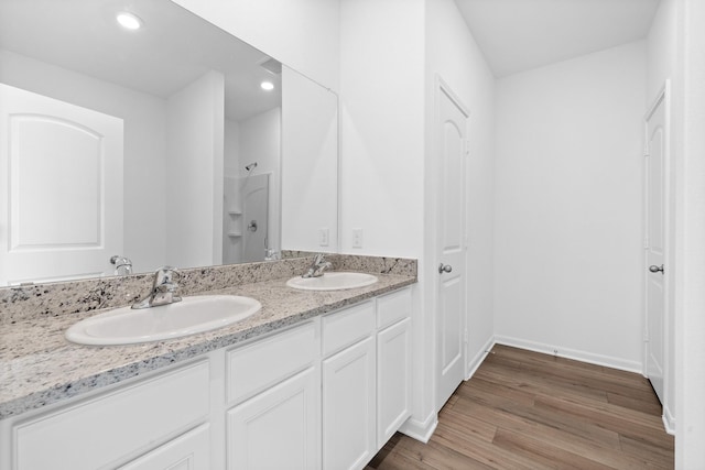 bathroom featuring walk in shower, vanity, and wood-type flooring