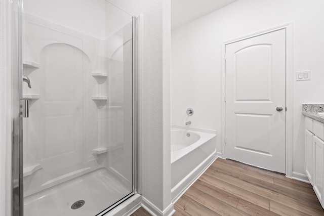 bathroom featuring plus walk in shower, hardwood / wood-style floors, and vanity