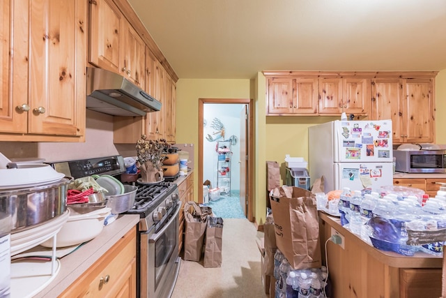 kitchen featuring light brown cabinetry, tile counters, appliances with stainless steel finishes, and light carpet