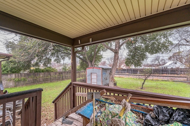 wooden terrace with a storage shed and a lawn