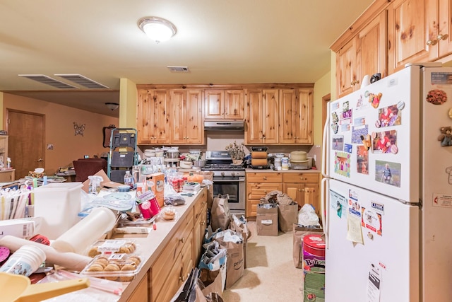 kitchen featuring light brown cabinetry, stainless steel range with gas cooktop, and white refrigerator