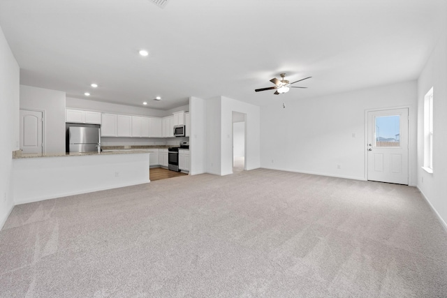 unfurnished living room featuring ceiling fan and light carpet