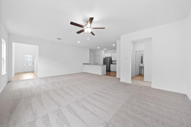 unfurnished living room with ceiling fan and light colored carpet