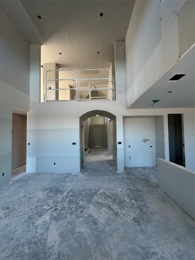 unfurnished room featuring concrete floors and a high ceiling