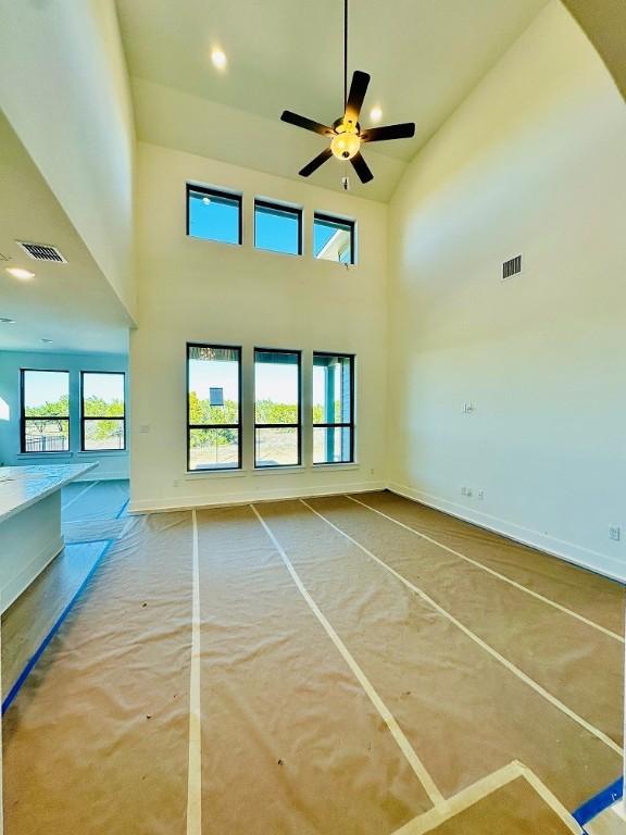 unfurnished living room featuring a towering ceiling