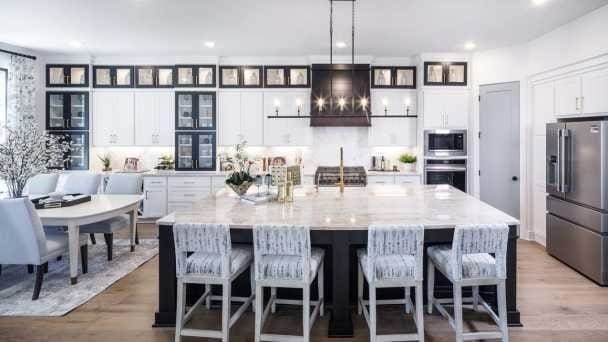 kitchen featuring a kitchen island with sink, pendant lighting, stainless steel appliances, and white cabinetry