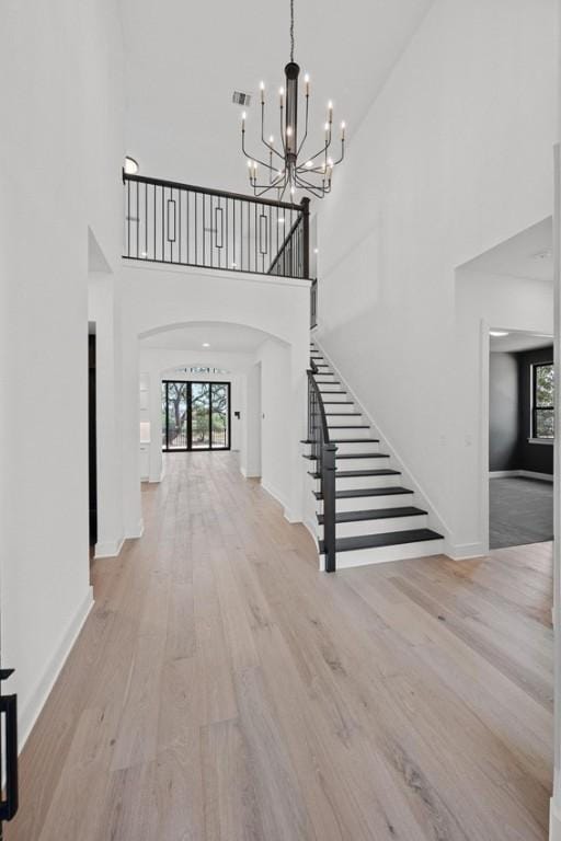 162 Leaning Rock Rdg, Austin, TX 78737 - foyer featuring arched walkways, healthy amount of natural light, a high ceiling, a chandelier, and wood finished floors
