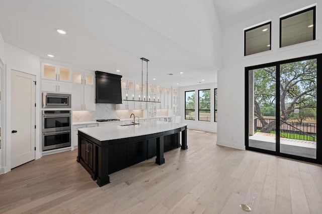 162 Leaning Rock Rdg, Austin, TX 78737 - kitchen with appliances with stainless steel finishes, light countertops, light wood-style flooring, tasteful backsplash, and a center island with sink