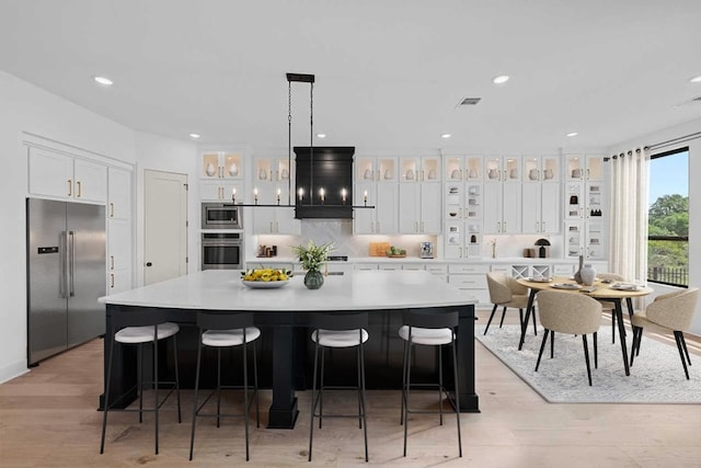 162 Leaning Rock Rdg, Austin, TX 78737 - kitchen with built in appliances, white cabinets, light wood-style flooring, a spacious island, and light countertops