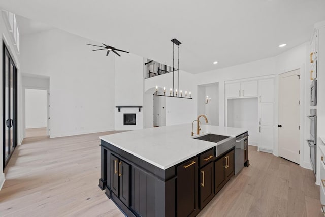 162 Leaning Rock Rdg, Austin, TX 78737 - kitchen with stainless steel appliances, light wood finished floors, white cabinetry, a large fireplace, and a center island with sink